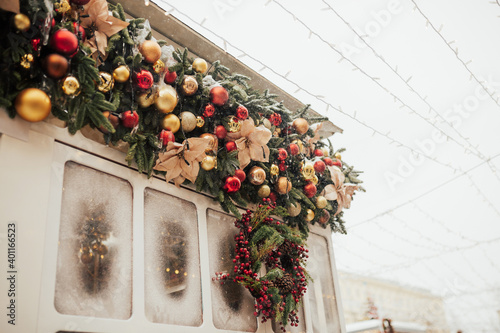 Cozy Christmas decor. Red and golden balls and Christmas wreath on store front or building facade. Christmas festive street decor, holiday winter fair. 