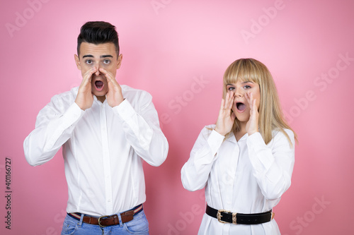 Young couple of girlfriend and boyfriend over isolated pink background shouting and screaming loud to side with hands on mouth
