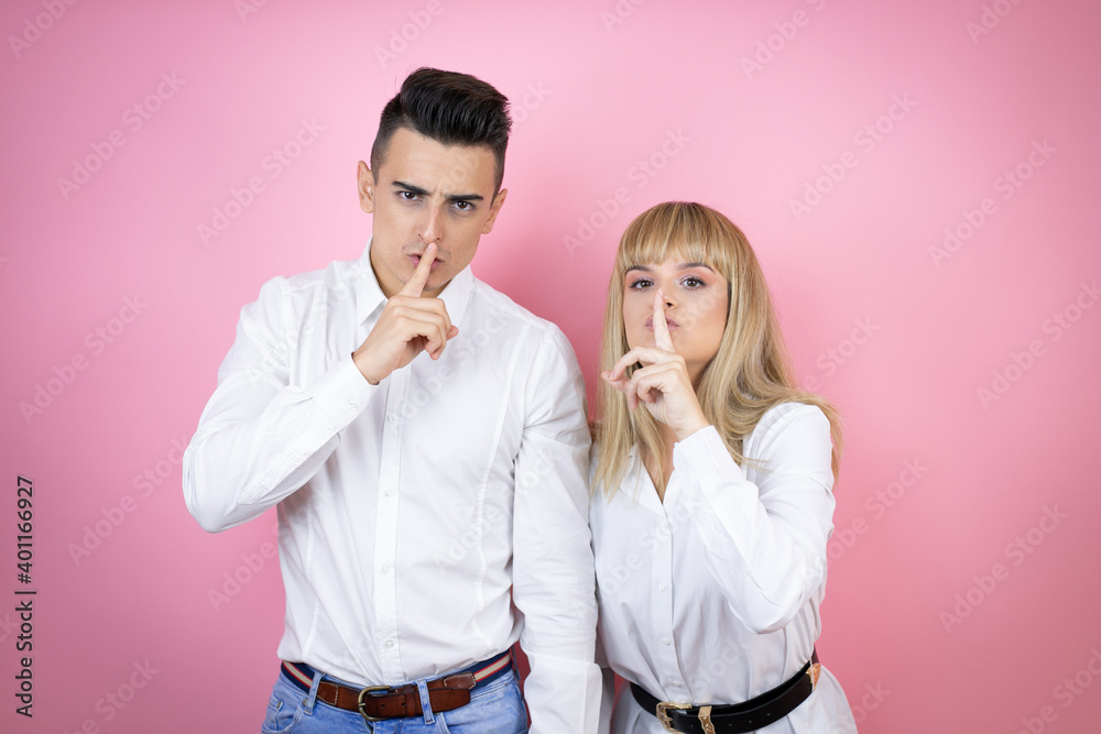 Young couple of girlfriend and boyfriend over isolated pink background asking to be quiet with finger on lips. Silence and secret concept. Young couple of girlfriend and boyfriend over isolated pink background asking to be quiet with finger on lips. Silence and secret concept.