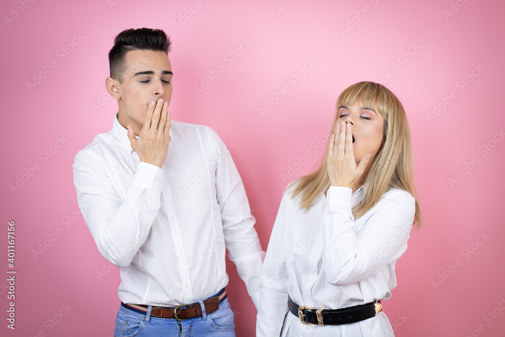 Obraz premium Young couple of girlfriend and boyfriend over isolated pink background bored yawning tired covering mouth with hand. Restless and sleepiness.