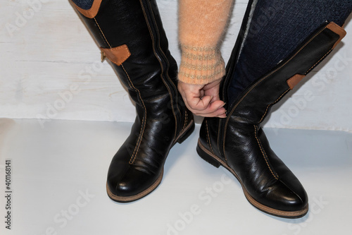 The woman puts on warm leather boots, zipper up.