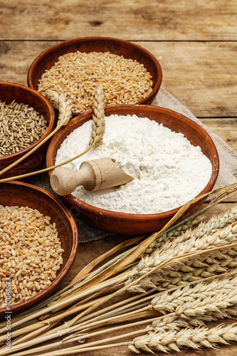 Ingredients for baking bread: wheat ears and a bowls of flour and grains