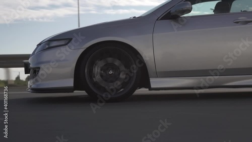 Side view of modern powerful car rides on summer highway. Footage. Perfect auto drives fast on country road.