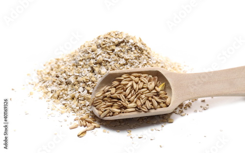 Oat bran pile and peeled groats with wooden spoon isolated on white background