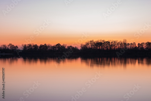 Landschaft und Sonnenuntergang mit Ufer des Sarchinger Weiher mit Spiegelung des Himmels in dem glatten See mit wunderschönen Farben Farbenspiel ohne Wolken, Deutschland