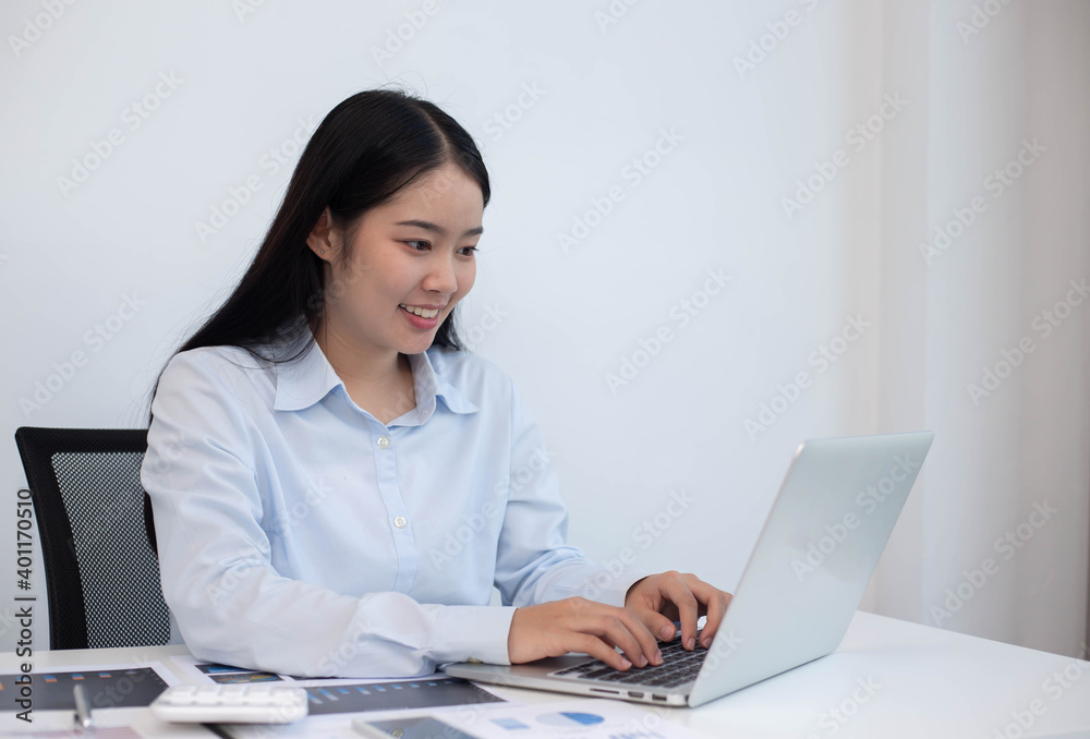 An Asian business woman sits at a desk with a laptop computer in a modern office. An Asian business woman sits at a desk with a laptop computer in a modern office.