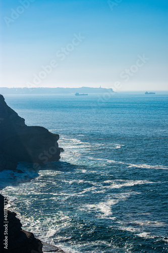 coastline cut into the ocean with boats and lighthouse Cabo Mayor