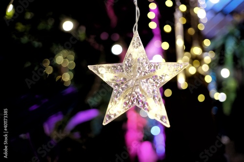 Blurred a female hand holding a star  hanging ornament Chirstmas decoration with light bokeh in the dark night 