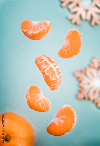 tangerines on a blue background. orange tangerine with slices and wooden Christmas tree decor on the table. wooden snowflakes and tangerines on the table