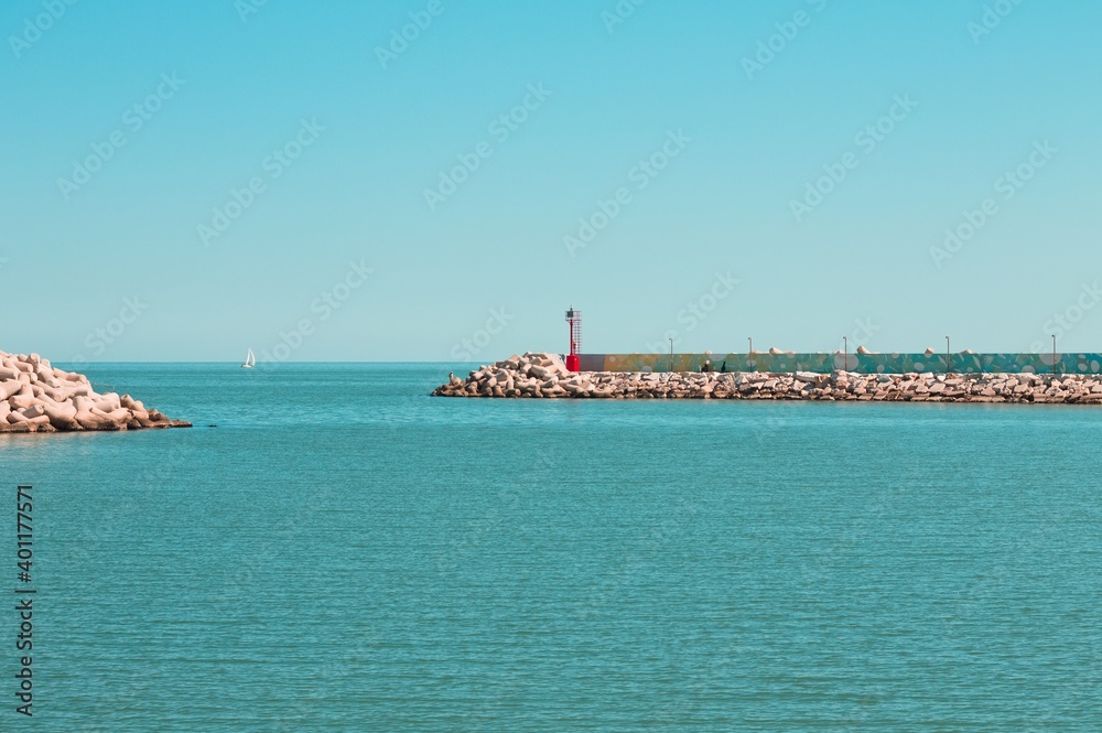 A red lighthouse on the jetty of Pesaro harbor with tetrapod breakwaters (Marche, Italy, Europe)