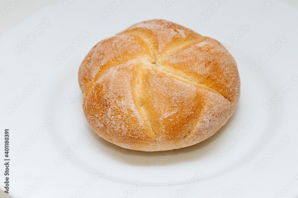 Chubby fresh round bun made of white flour on a plate