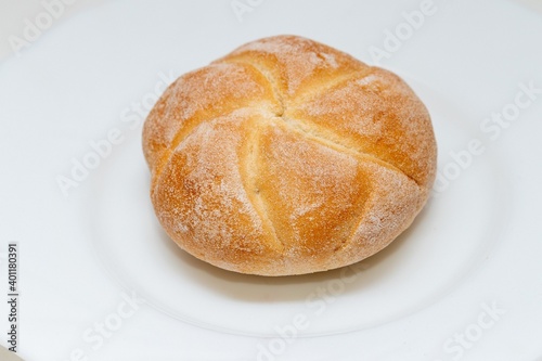 Chubby fresh round bun made of white flour on a plate