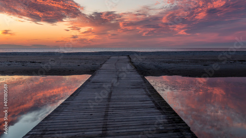 Beautiful sunset. golden, orange, blue colors over the sea. sky full of many colors. bridge over a small lake where the sky is reflected in