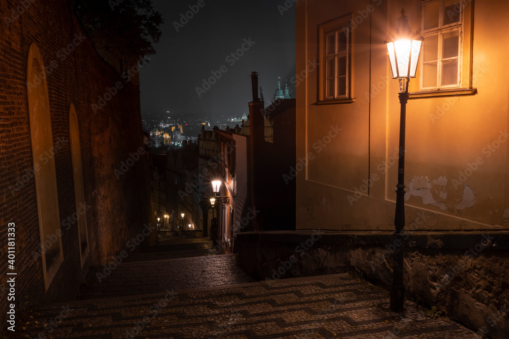 lights and pedestrian sidewalk with cobblestones in the center of Prague at night and in the background city view at night
