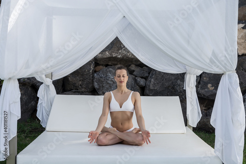 Calm woman practicing yoga in Lotus pose on bed