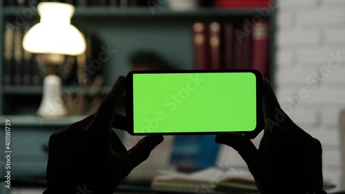 Close up Horizontal hands holding smartphone with green screen at home. Green screen mobile phone with chroma key. Guy Using Mobile Phone, Internet Social Networks Browsing.