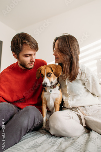 happy couple in love with a beagle dog sitting on the bed