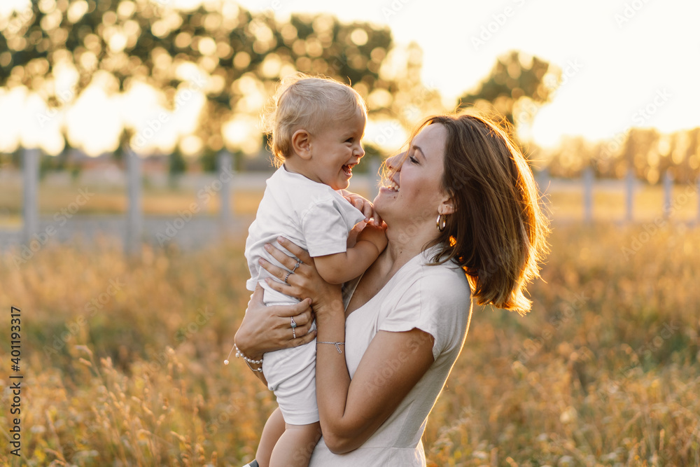 Fototapeta premium Woman playing with her child on the field during sunset.