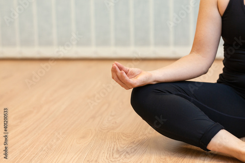 woman sitting in yoga position and meditating isolated over parquet