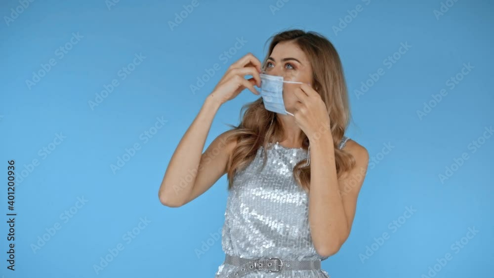 Smiling woman wearing medical mask isolated on blue Smiling woman wearing medical mask isolated on blue