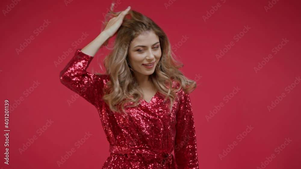 Woman in dress fixing hair and smiling isolated on red Woman in dress fixing hair and smiling isolated on red
