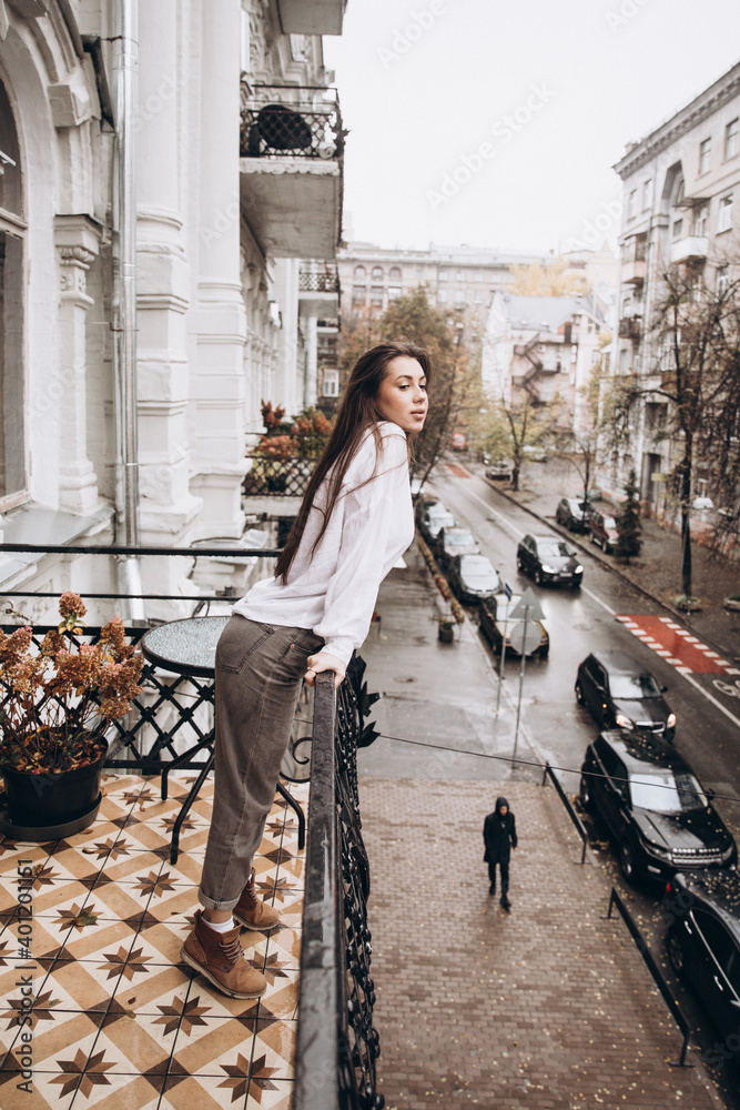 Fototapeta premium Photoshoot of a beautiful girl in a white shirt on the balcony