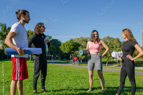 Group of Friends Having a Talk Before Yoga Class at the Park in Sunny Day with Tap on Hand
