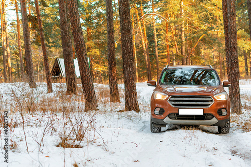 Orange crossover car on the road in the pine winter forest