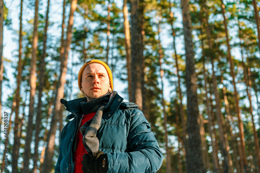 Young man in winter yellow hat walks in winter snowy pine forest Young man in winter yellow hat walks in winter snowy pine forest