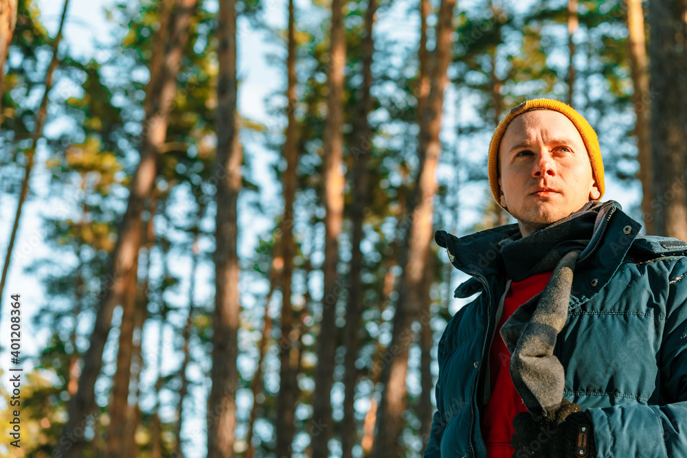 Young man in winter yellow hat walks in winter snowy pine forest Young man in winter yellow hat walks in winter snowy pine forest