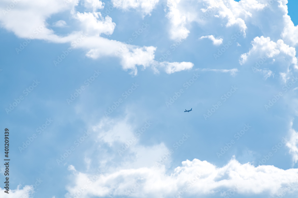 Airplane flying in the blue sky among clouds and sunlight