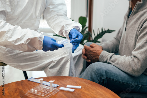 Close up of medical staff hands preparing the nasal swab to proceed to take a nasal culture sampling from a man at his home. Rapid Antigen Test for Covid-19. photo