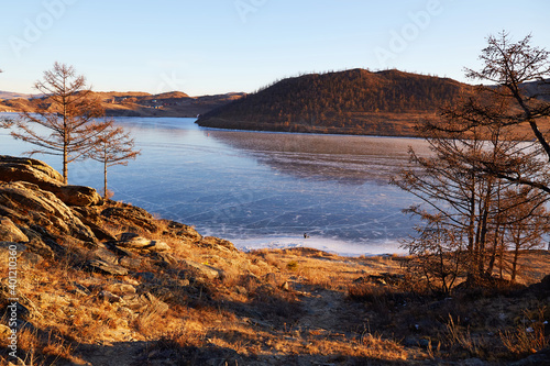 Fototapeta Naklejka Na Ścianę i Meble -  Lake Baikal in December. View of the frozen Kurkut Bay. Larch trees on the lake shore.