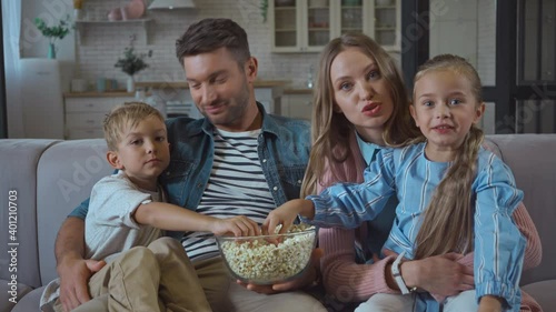 Family with popcorn talking while looking at camera at home photo