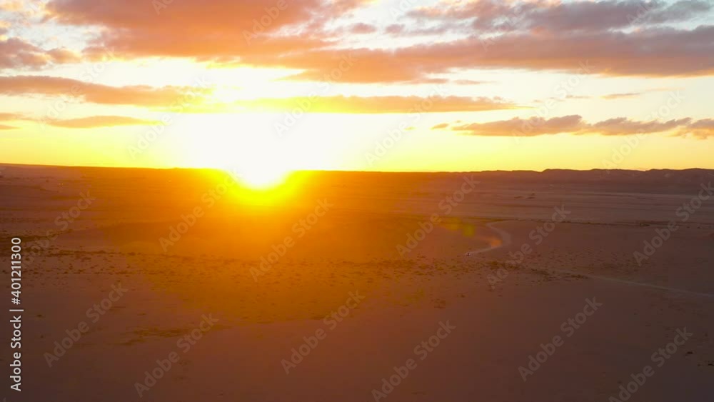 Scenic aerial shot of desert sunset. Dramatic vivid colors at golden hour. Bright sky horizon drone pan shot panoramic view Scenic aerial shot of desert sunset. Dramatic vivid colors at golden hour. Bright sky horizon drone pan shot panoramic view