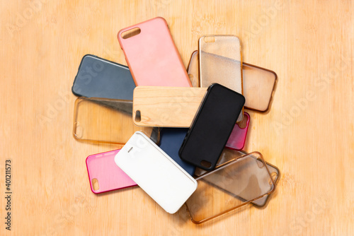 Pile of multicolored plastic back covers for mobile phones on wooden table background