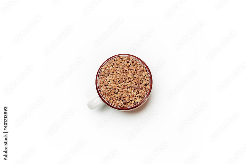 Fototapeta premium Top view of uncooked buckwheat grain seeds in the ceramic cup isolated on the white background