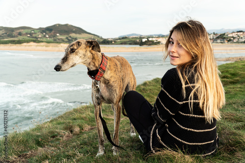 Young blonde woman and her greyhound on the shore