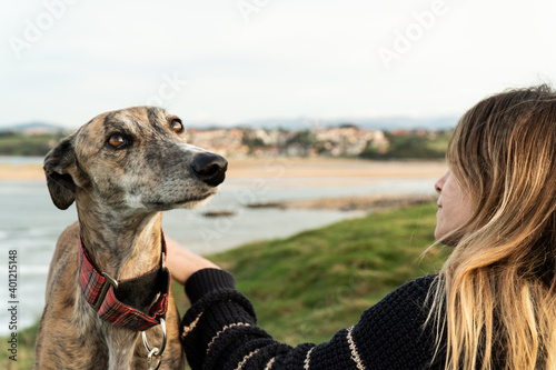 Young blonde woman and her greyhound on the shore
