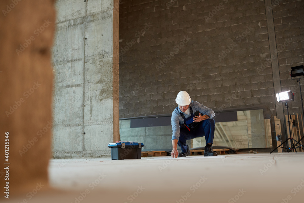 Wide angle view of female construction worker marking floor while working in apartment building, copy space