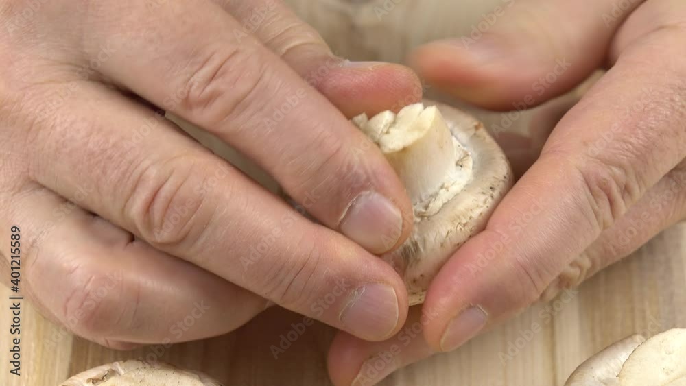Man prepares mushrooms for cooking, separating the caps from the stipes. Man prepares mushrooms for cooking, separating the caps from the stipes.