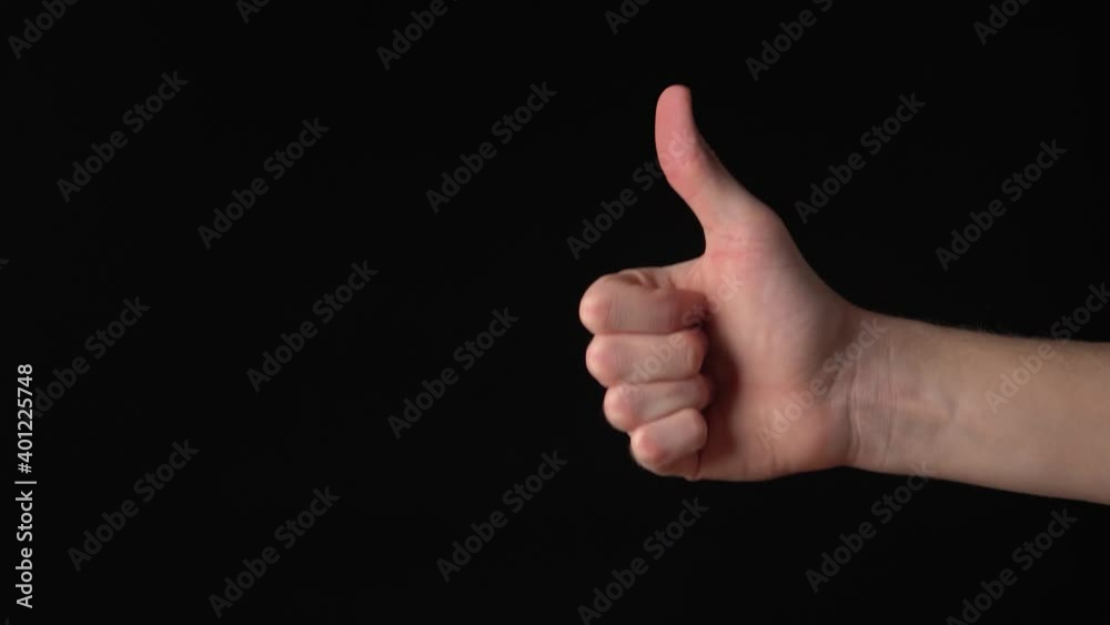 Young caucasian man's hand showing thumb up on black background. Isolated Young caucasian man's hand showing thumb up on black background. Isolated