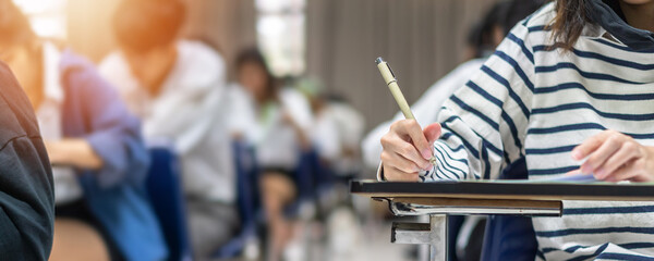 Exam at school with student's taking educational admission test in class, thinking hard, writing answer in university classroom, education and world literacy day concept