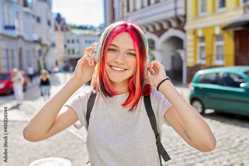 Outdoor portrait of teenage girl listening music with wireless headphones