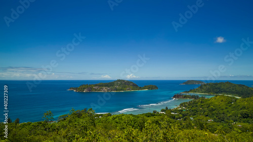 Panoramic view of the densely overgrown green Seychelles washed by turquoise water, the horizon is buried in the sea.