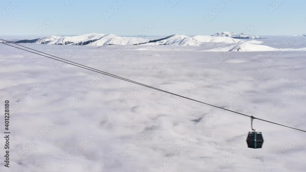 Timelapse of ski gondolas above a sea of clouds in Winter, above Sinaia ski resort in Romania, with snow covered mountain peaks in the distance. Temperature inversion, cloud inversion. Timelapse of ski gondolas above a sea of clouds in Winter, above Sinaia ski resort in Romania, with snow covered mountain peaks in the distance. Temperature inversion, cloud inversion.