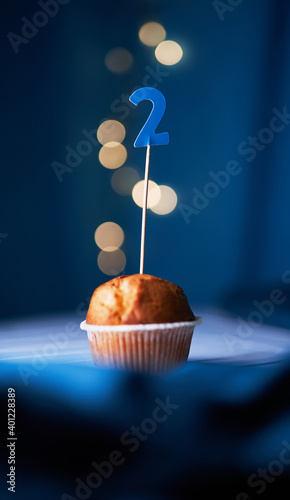 Birthday cake or muffin with number two (2) and lights on the blue background. Birthday or anniversary concept photo