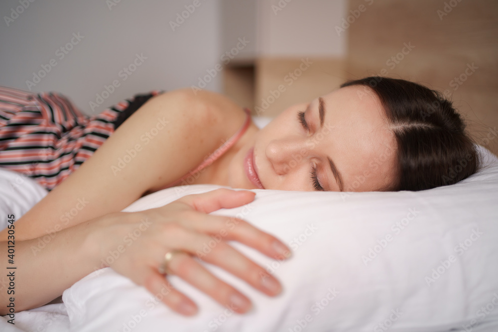 Caucasian woman sleeping in bed. Lady enjoys fresh soft bedding linen and mattress in bedroom Caucasian woman sleeping in bed. Lady enjoys fresh soft bedding linen and mattress in bedroom