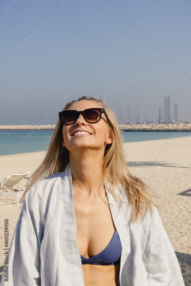Smiling girl in a swimwear and sunglasses enjoying vacation at the beach on a summer day. Smiling girl in a swimwear and sunglasses enjoying vacation at the beach on a summer day.