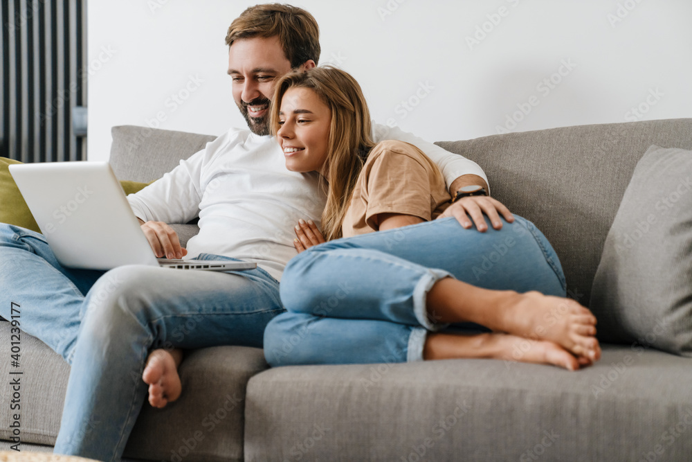 Happy couple at home relaxing with laptop